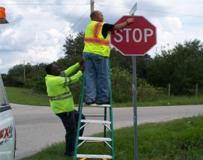 two men installing a stop sign at an intersection